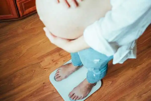 Image of woman weighing herself and experiencing weight gain through pregnancy Brentwood